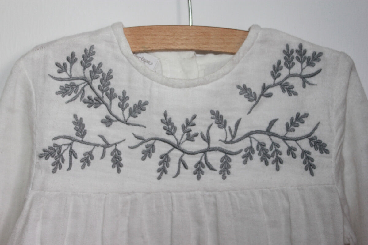 Preloved katoenen witte blouse met grijs geborduurde bloemen op de borst en lange mouwen van Fina Ejerique in maat 116 